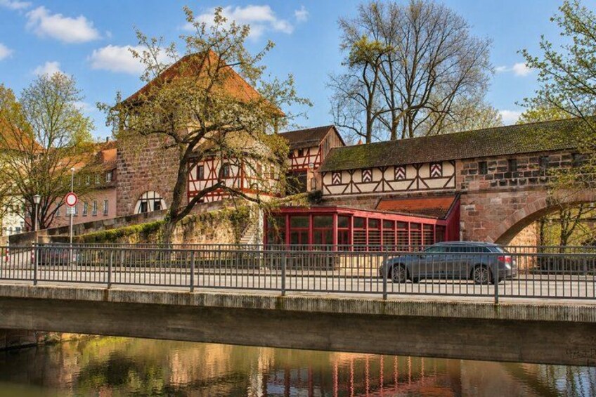 A historic building with a red facade, a bridge, and a calm river reflecting the structure. 4