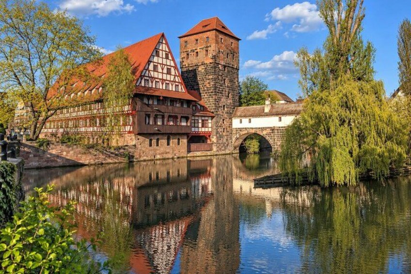 A historic town with a river, a bridge, and traditional half-timbered houses. 3