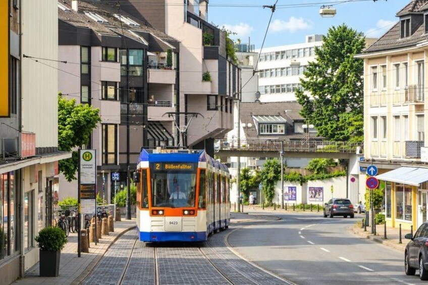 A tram on a city street with buildings and a pedestrian crossing. 4
