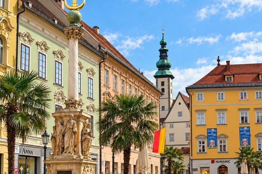 A street with historic buildings, palm trees, and a statue. 2