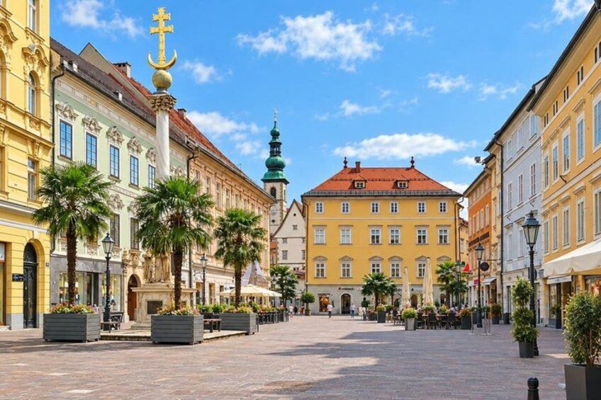 A European square with historic buildings, palm trees, and a prominent tower. 3