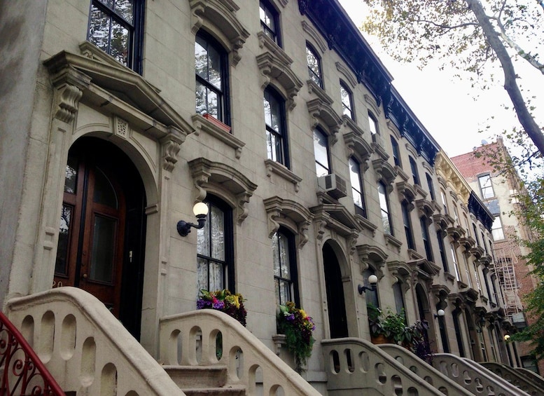 Una hilera de edificios históricos con detalles arquitectónicos ornamentales, incluyendo ventanas en arco y molduras decorativas. 3