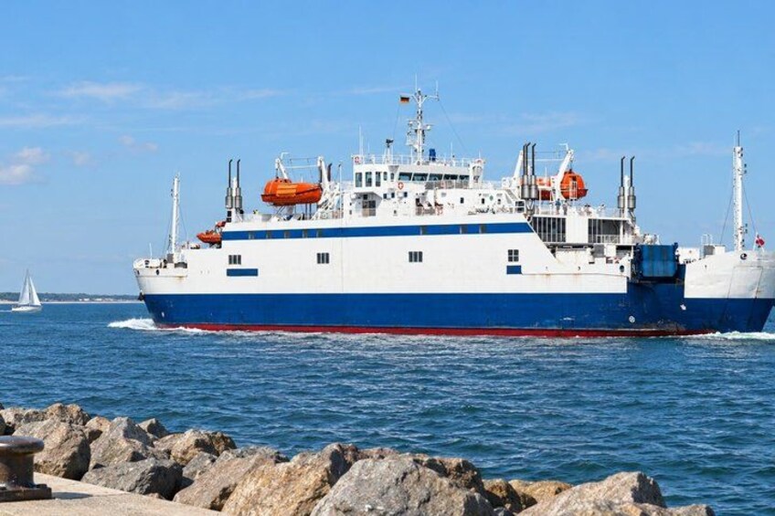 A large cargo ship with blue and white hulls, orange lifeboats, and a clear sky in the background. 2