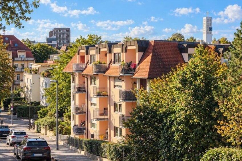 A residential area with multi-story buildings, parked cars, and a clear sky. 5