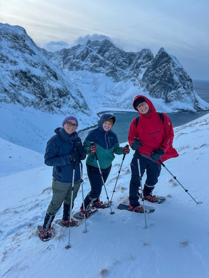 Three people skiing on a snowy mountain slope with a lake and mountains in the background. 3