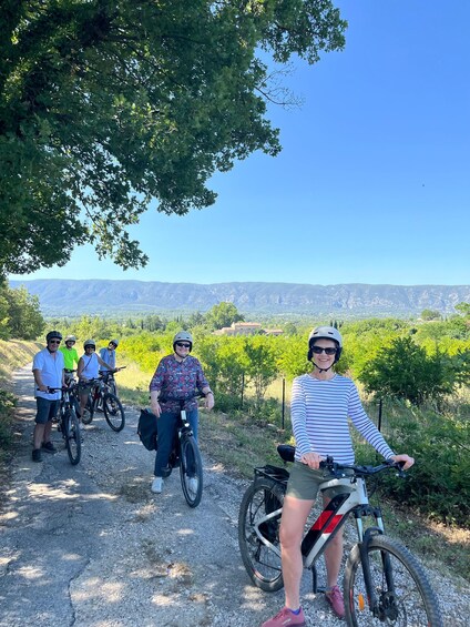 A group of people on bicycles on a gravel path with a mountainous landscape in the background. 1