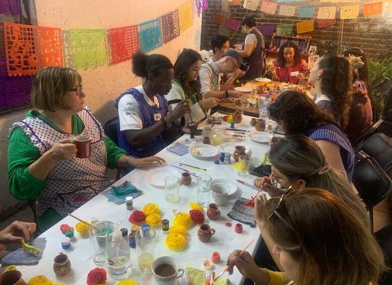 Un grupo de personas participa en una actividad artesanal alrededor de una mesa con diversos materiales y herramientas. 4