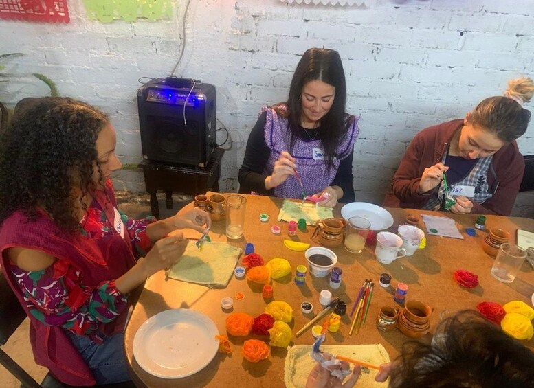 Un grupo de personas participa en una actividad de pintura en una mesa con diversos materiales. 2