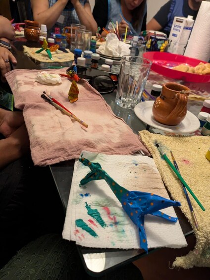 Una mesa con materiales de arte, incluyendo pinceles, pintura y figuras de arcilla. 5