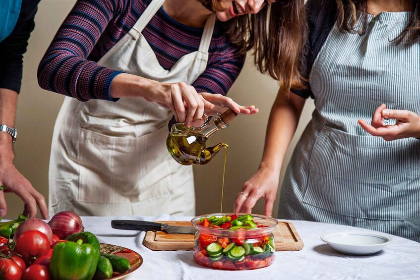 People preparing a salad with a jar of dressing. 2