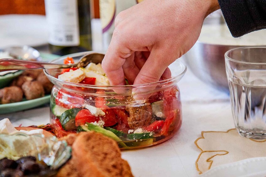 A hand picking up a glass jar filled with a salad. 3