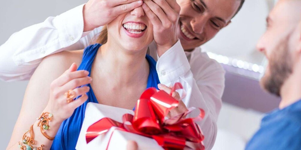 Una persona sosteniendo un regalo con un lazo rojo. 3
