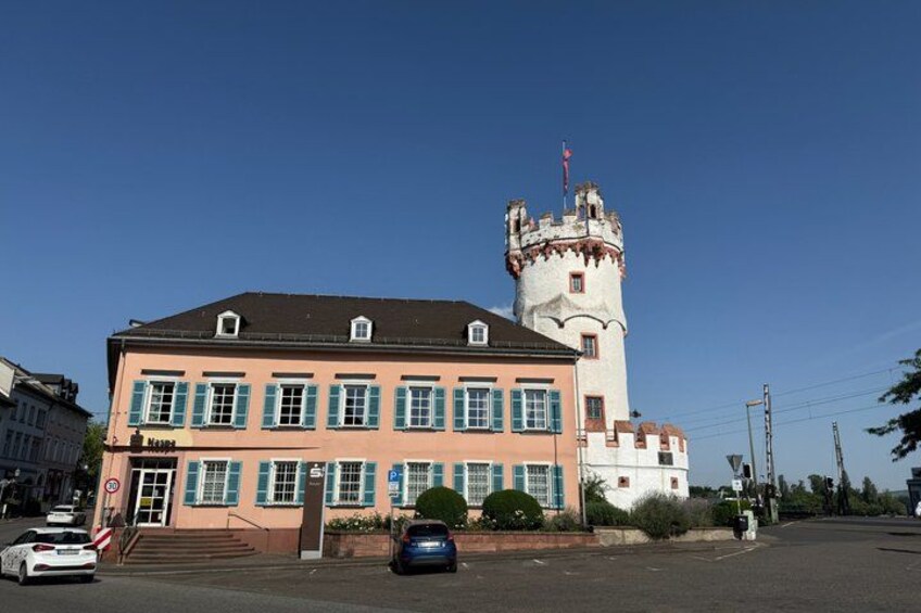 A castle with a tower, a building with blue shutters, and a clear blue sky. 5