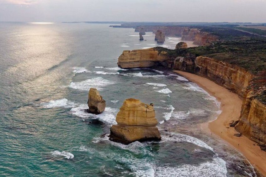A coastal landscape with prominent rock formations and a sandy beach. 2