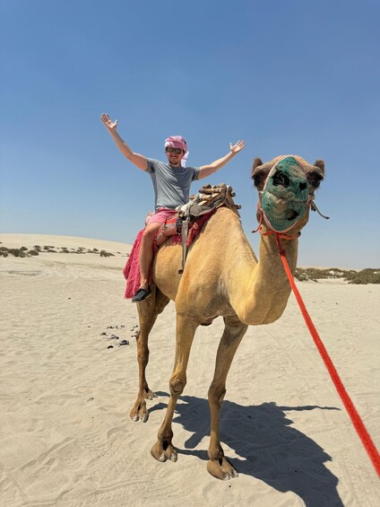 A person riding a camel in a desert with sand dunes in the background. 2