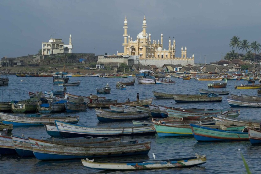 Un puerto con numerosos barcos pequeños, una mezquita destacada con varios minaretes, y un pueblo costero con edificios. 1