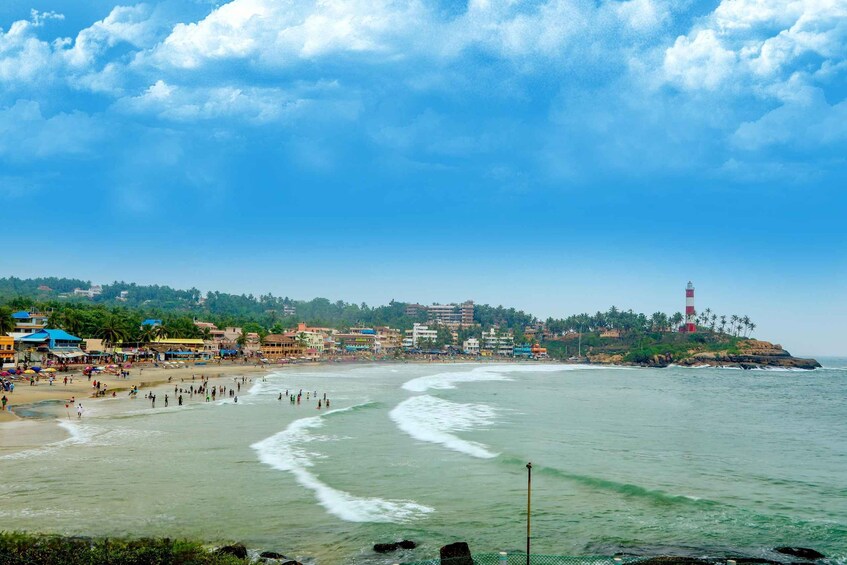 Una playa con gente, olas, edificios y un faro. 3
