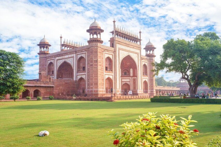 A large, historic building with multiple domes and arches, surrounded by a well-maintained lawn and trees. 2