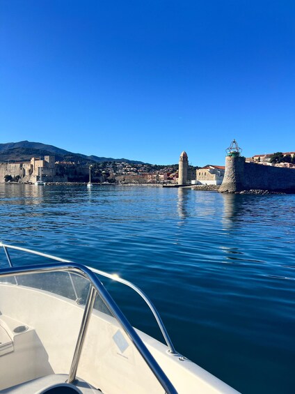 Un pueblo costero con una torre y fortaleza destacadas, aguas tranquilas y un cielo azul despejado. 2