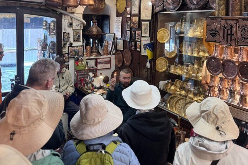 A crowded market with people browsing and a shop window displaying various items. 4