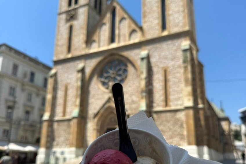 A scoop of ice cream with a spoon in front of a historic church. 2