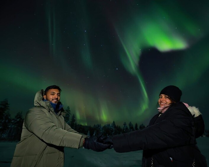 Two people holding hands under the Northern Lights. 1