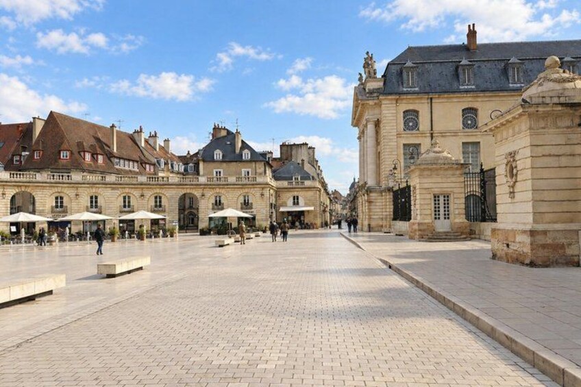 A historic square with cobblestone pavement, classical architecture, and a clear sky. 2