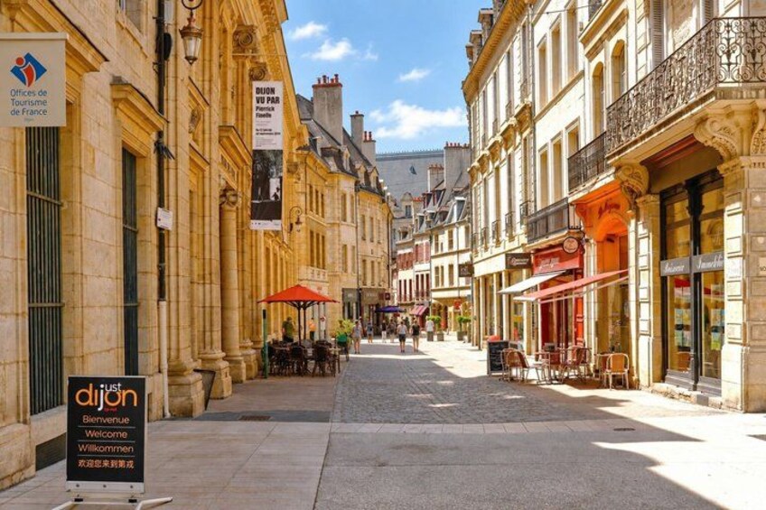 A street with buildings, outdoor seating, and a sign for Offices de Tourisme de France. 3