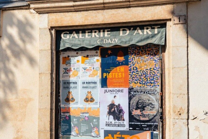 A storefront with a sign reading 'GALERIE D'ART' and various posters advertising events and exhibitions. 5