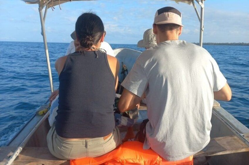 A boat with two people on board, one wearing a black top and the other in a white shirt, with a calm sea in the background. 4