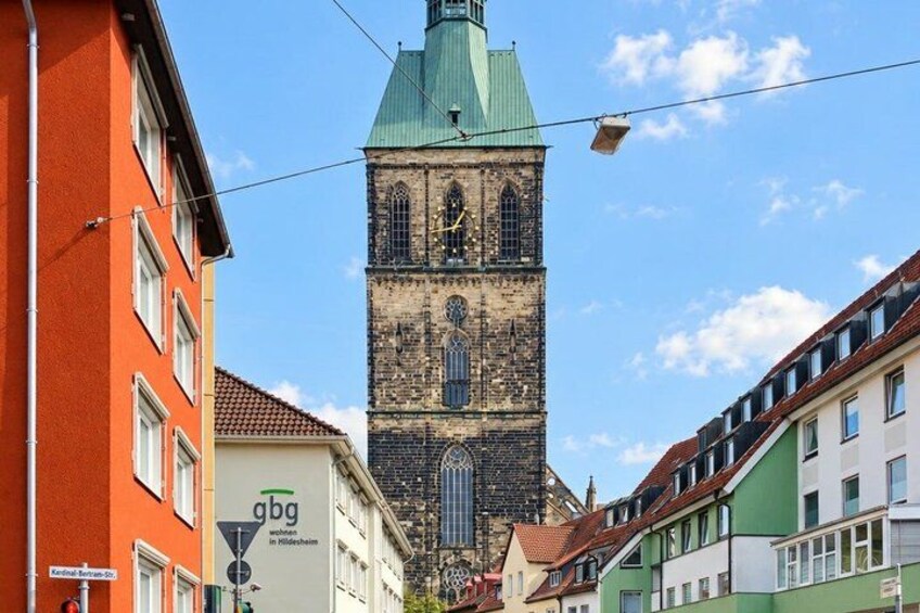 A historic tower with a green roof, surrounded by colorful buildings. 4