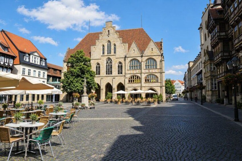 A cobblestone street with outdoor seating, historic buildings, and a large church with a prominent tower. 5