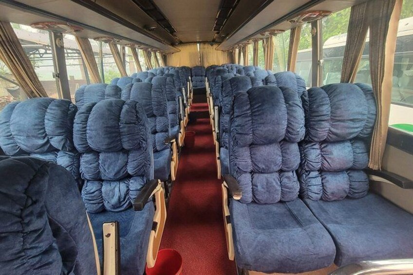 A train interior with rows of blue upholstered seats and a red carpet aisle. 5