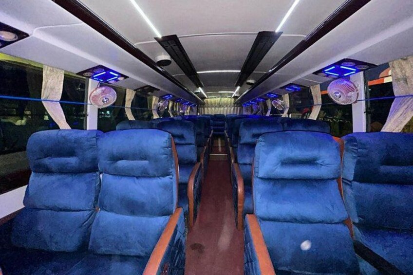 A train interior with blue upholstered seats, overhead luggage racks, and blue ambient lighting. 3