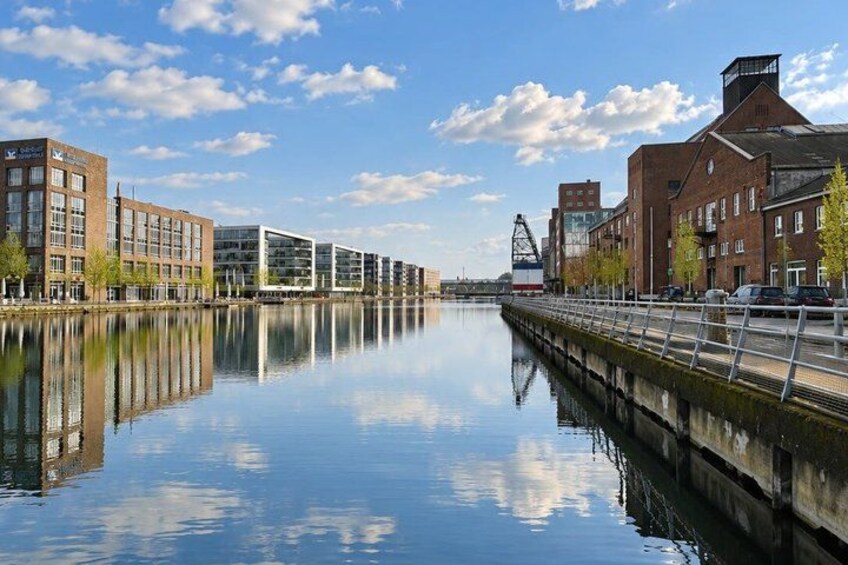 A calm river with buildings on both sides, a clear sky, and a bridge in the distance. 5