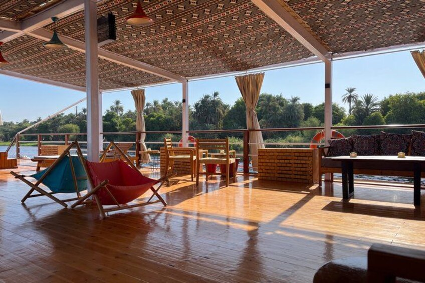 An outdoor deck with wooden flooring, a hammock, and a table with chairs. 2