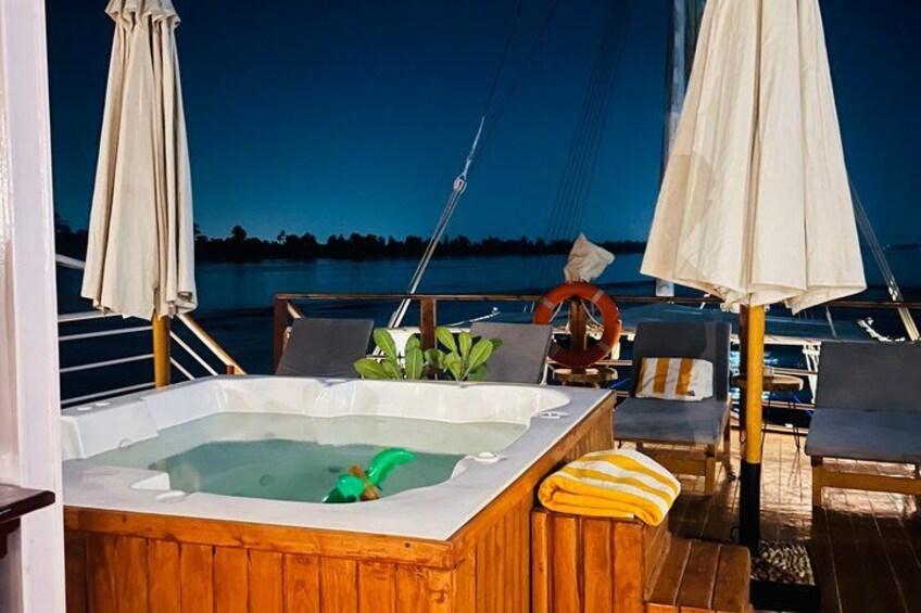 A hot tub on a wooden deck with lounge chairs and umbrellas. 3