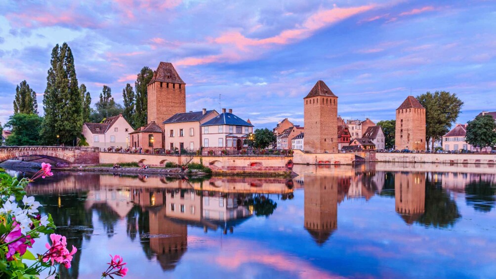A historic town with a river, reflecting buildings and towers, and a bridge. 4