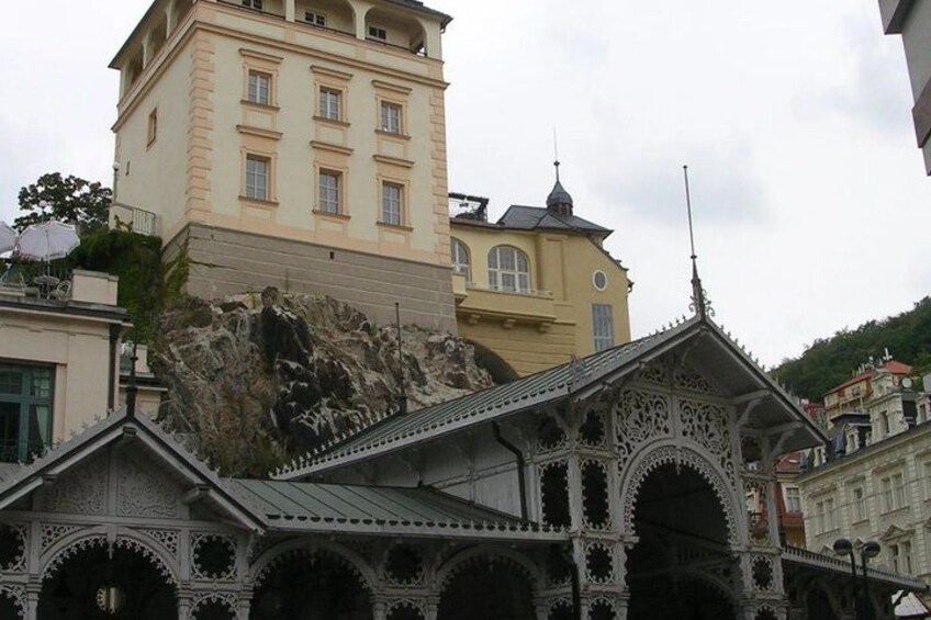 A building with ornate architectural details, a large rock formation, and a staircase leading up to it. 3
