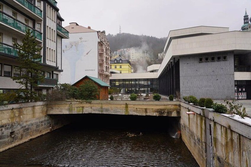 A bridge over a river, buildings, and a hill in the background. 5