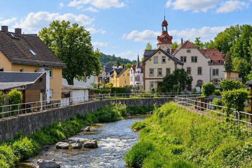 A river flowing through a town with buildings and a church in the background. 3