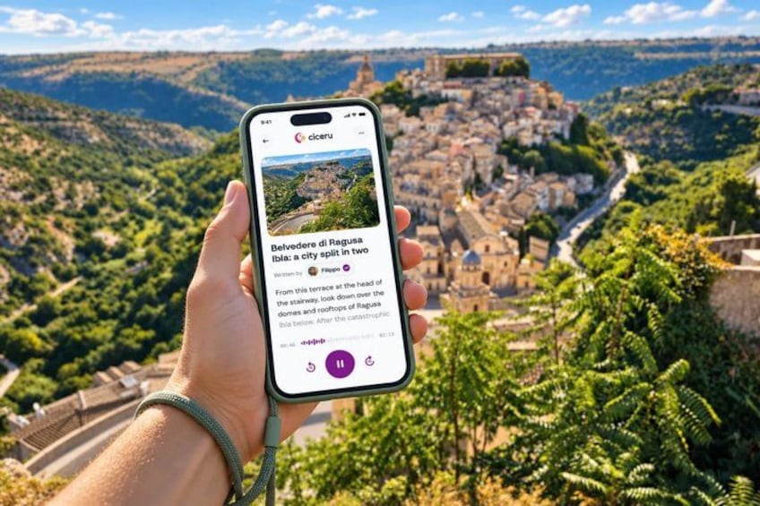A hand holding a smartphone displaying a scenic view of a city with a historic fortress in the background. 1