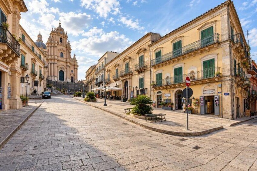 A cobblestone street lined with historic buildings, a church, and a café. 5