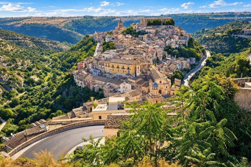 A historic town nestled in a valley with a prominent church and fortress on a hill. 3