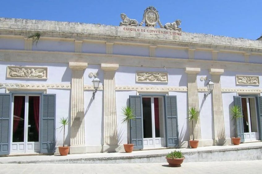 A building with columns, shutters, and a sign that reads 'CIRCOLO DI CONVERSAZIONE.' 4