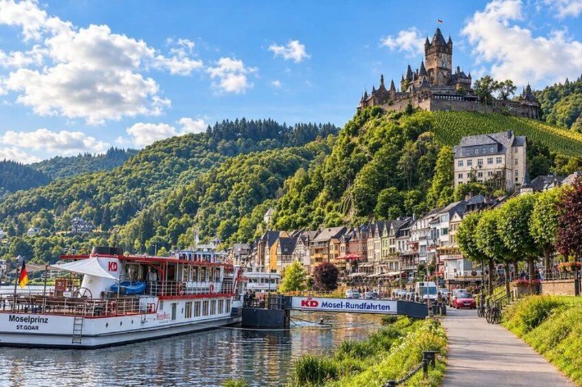 A river with boats, a castle on a hill, and a town with buildings. 2