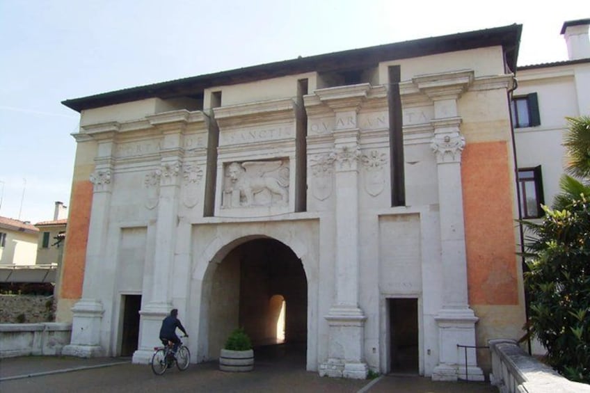 A white building with an arched entrance, columns, and decorative reliefs. 2