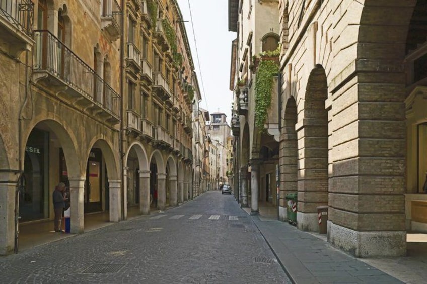 A cobblestone street lined with historic buildings, featuring arched doorways and balconies. 5