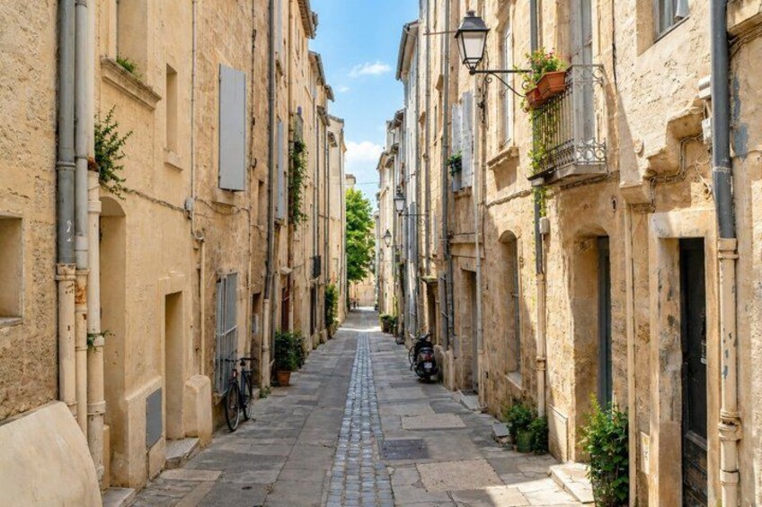 A narrow cobblestone street flanked by historic buildings with balconies and street lamps. 4