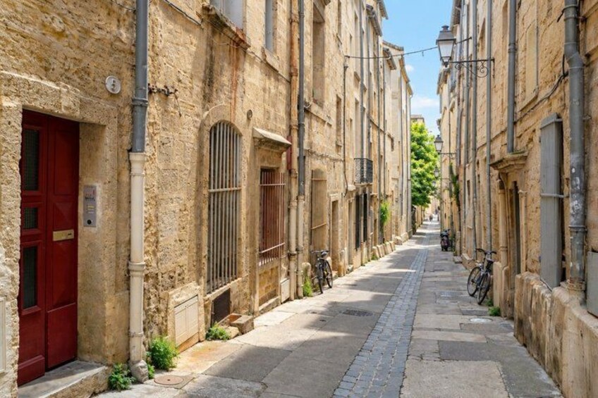 A narrow street lined with old stone buildings, a red door, and bicycles parked along the side. 2